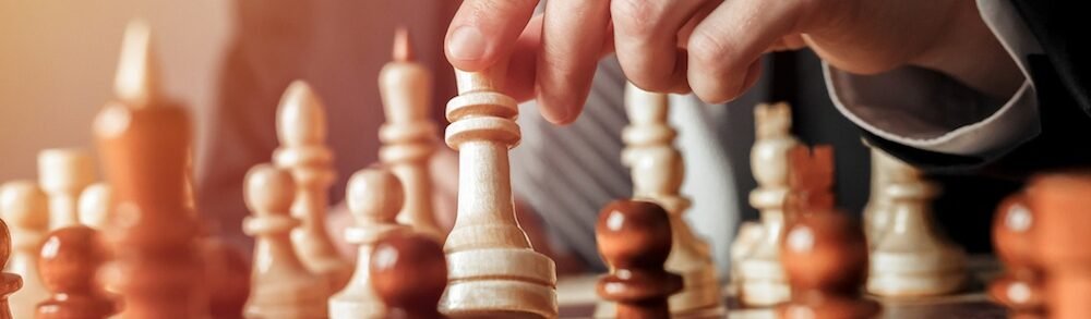 hand of businessman moving chess figure in chess play. strategy, management or leadership concept.